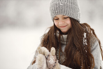 Portrait of a brunette girl in knitted hat and grey jacket at winter