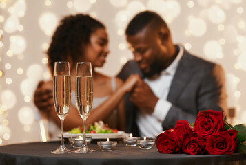 Two glasses of champagne and bunch of red roses over black couple in love, celebrating Valentine's Day at restaurant