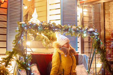 Young woman looks at festive Christmas city decorations.