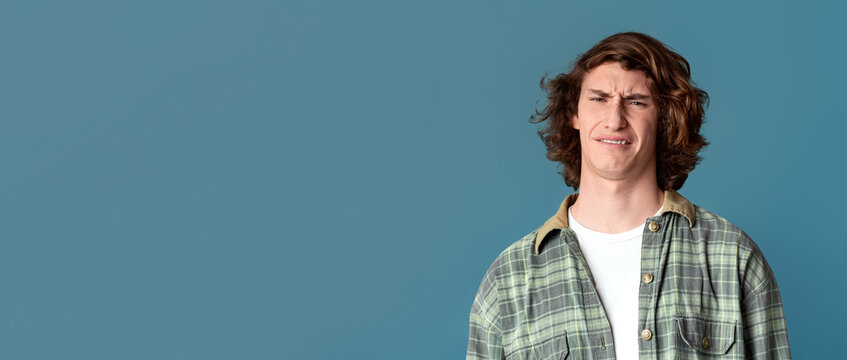 Young guy with disgusted expression on turquoise background