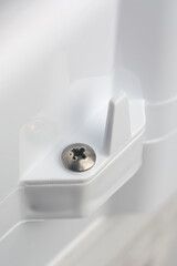 close-up of phillips crosshead screw head mounted on white textured plastic product or appliance...