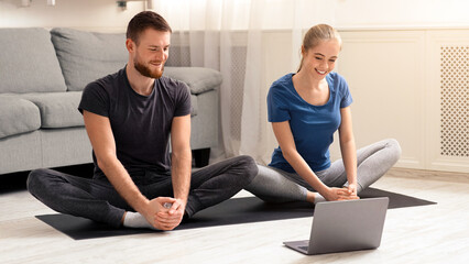 Online yoga practice. Millennial couple meditating at home near laptop