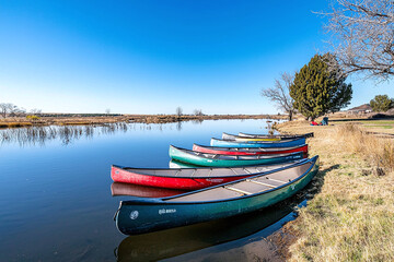 Obraz premium a serene lake with canoes docked along the shore, reflecting clear skies.
