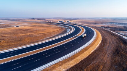 From an aerial view, trucks and cars are driving on the intersecting highway, and the clear blue sky is visible. Deep depth of field, showcasing busy roads and vehicles from the perspective of drones.