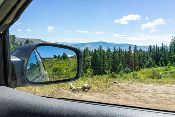 Eagle County Castle Peak park in Colorado with coniferous trees and landscape view from rear view passenger window near Emerald Lake