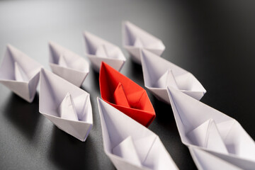 Row of paper ships on black background. Business concept of creative innovation and leadership.