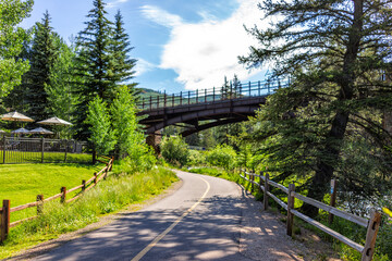 Vail, Colorado Lionshead Village park view of street bike walking trail, pedestrian path in summer along Gore creek river with bridge