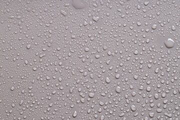 Water drops on gray background, top view