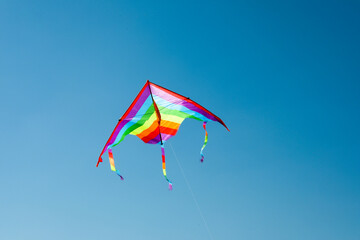 One colorful kite flying in blue sky