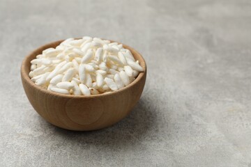 Puffed rice in bowl on light grey table, closeup. Space for text
