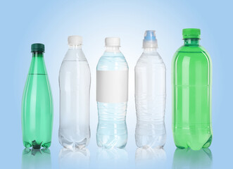 Different plastic bottles with water on light blue background