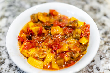 Ratatouille homemade chopped yellow summer zucchini squash vegetables macro closeup of bowl with red tomatoes and peppers dish meal