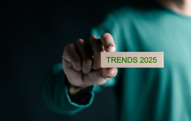 2025 trends concept. Person holding wooden block with trends 2025 text for setup objective target business cost and budget planning for new year.