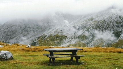 Obraz premium Serene mountain scene with a rustic wooden table, grass blowing gently and ridges stretching beyond