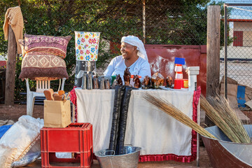 african street vendor selling cow bell and buckets, art and craft products, small entrepreneur...