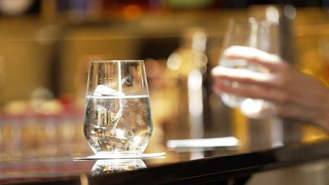 Closeup bartender hand serving fresh soda or tonic fizzy to customer while next guest taking glass to sip at beverage bar counter for advertisement of greeting guess service welcome drink. Vinosity.