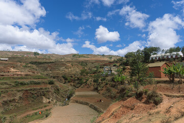 Expansive rural landscape with patches of green and brown fields under a cloudy sky. Rural landscape, Isalo National Park, Madagascar.