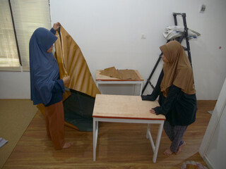 Asian muslim women, mother and daughter doing crafts work, covering table with wooden textured vinyl