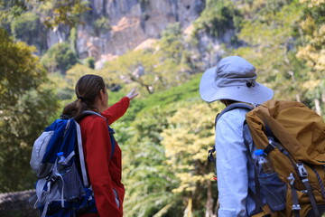Two Senior women hiking and walking in  the autumn forest and exploring  the rock cave in the...