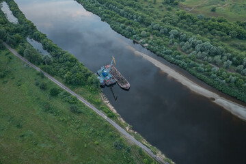 A breathtaking aerial view showcasing a serene riverbank featuring a tugboat amidst lush greenery