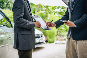 An Asian businessman buys a car, signs a contract with the salesman, and receives the keys. They discuss essential terms, covering car leasing, finance, and loan laws to finalize the purchase