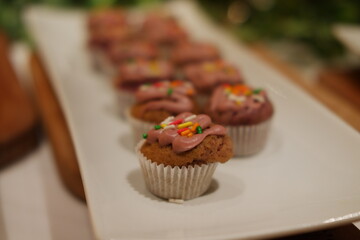 small cupcakes topped with pink frosting and colorful sprinkles