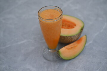 Melon juice in a glass and fresh melon on the table