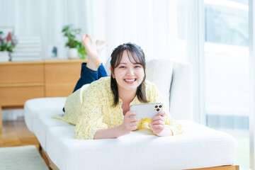 部屋でスマホを操作する若い女性