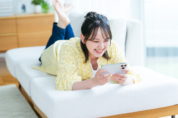 部屋でスマホを操作する若い女性