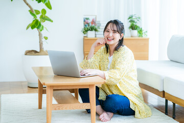 自宅でノートパソコンを操作する若い女性