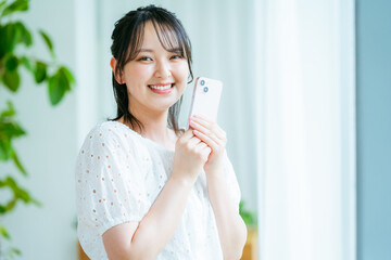 部屋でスマホを操作する若い女性