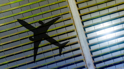 Airplane shadow gliding over massive solar panel installation during sunny day. Sustainable aviation and renewable energy integration for eco friendly transportation future at commercial solar farm.