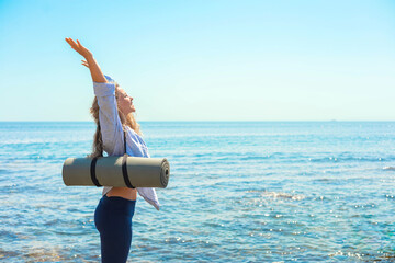 Happy yoga woman celebrate win with raising hands at sunny sea sky