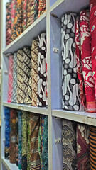 piles of batik cloth on the shelves of a typical Indonesian fabric shop