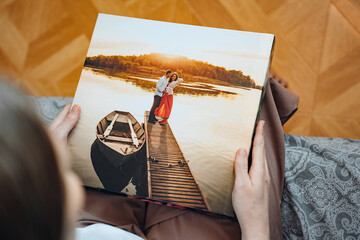 woman is holding and flipping through a photo book with a pregnancy photo shoot