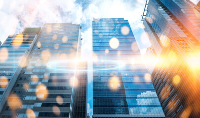 A low angle shot of tall buildings reaching towards a bright, sun-drenched sky, with a blurred...