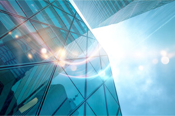 A low angle view of modern glass skyscrapers with sun glare reflecting off the windows.