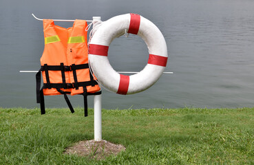 rescue life jacket and lifebuoy hanging on waterfront lawn post
