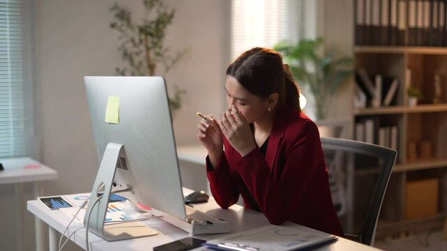 Businesswoman showing stress and frustration while working at her desk on a computer, overwhelmed by work demands