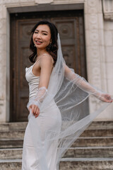Elegant Bride gracefully poses on the Stairs wearing a Beautiful Wedding Dress