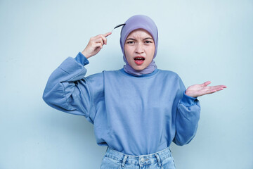 Asian Muslim woman is fasting and hungry and holding cutlery while looking a camera thinking about what to eat.