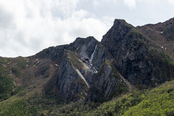 A small waterfall gently flows over the top of a cliff face in Gros Morne, adding to the tranquil and majestic landscape of this stunning national park.