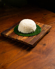Only white rice served on banana leaf on wooden table