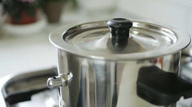 Man in the Kitchen Put the Lid on the Pot of Boiling Milk which making Steam.