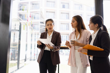 Asian businesswoman teamwork planning with sticky notes and new ideas on a glass wall, Business people brainstorming strategy and new ideas concept, startup worker meeting,