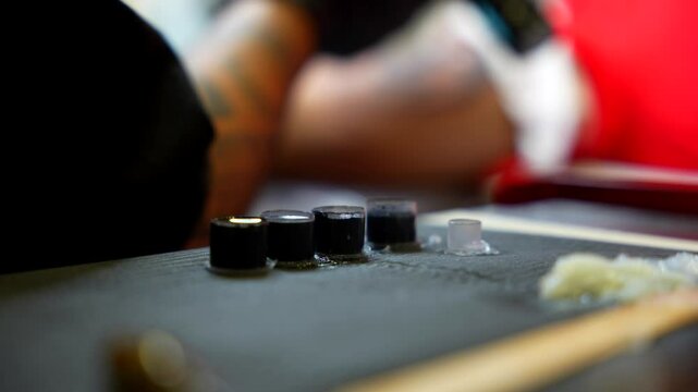 Ink caps and tools on a tattoo artist&rsquo;s workstation while takes some vaseline. Close up