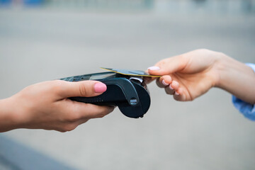 Customer using a payment terminal for contactless transaction at outdoor market.