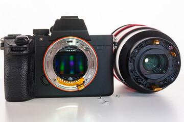 A broken lens, professional camera and repair tools on a white table.