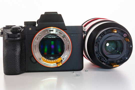 A broken lens, professional camera and repair tools on a white table.