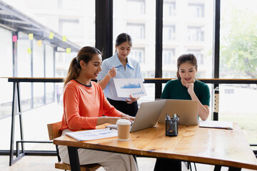 Fototapeta premium group of asian businesswoman working on laptop with finances analysis report at desk in office, business financing, accounting banking, Team of creative and business planning, 